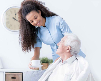 a caregiver giving a senior man his coffee