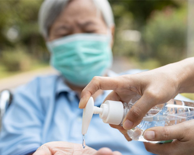 a senior man putting on a hand sanitizer