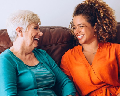 a caregiver and a senior woman smiling at each other